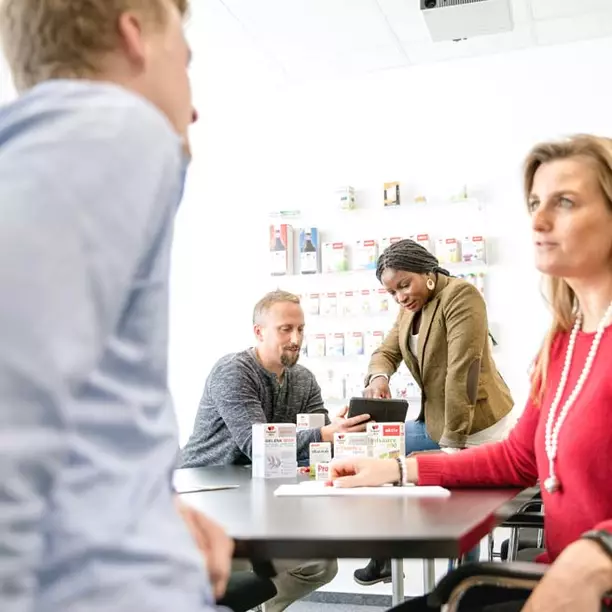 Gespräch zwischen Mitarbeiter*innen im Büro mit Doppelherz-Produkten auf dem Tisch